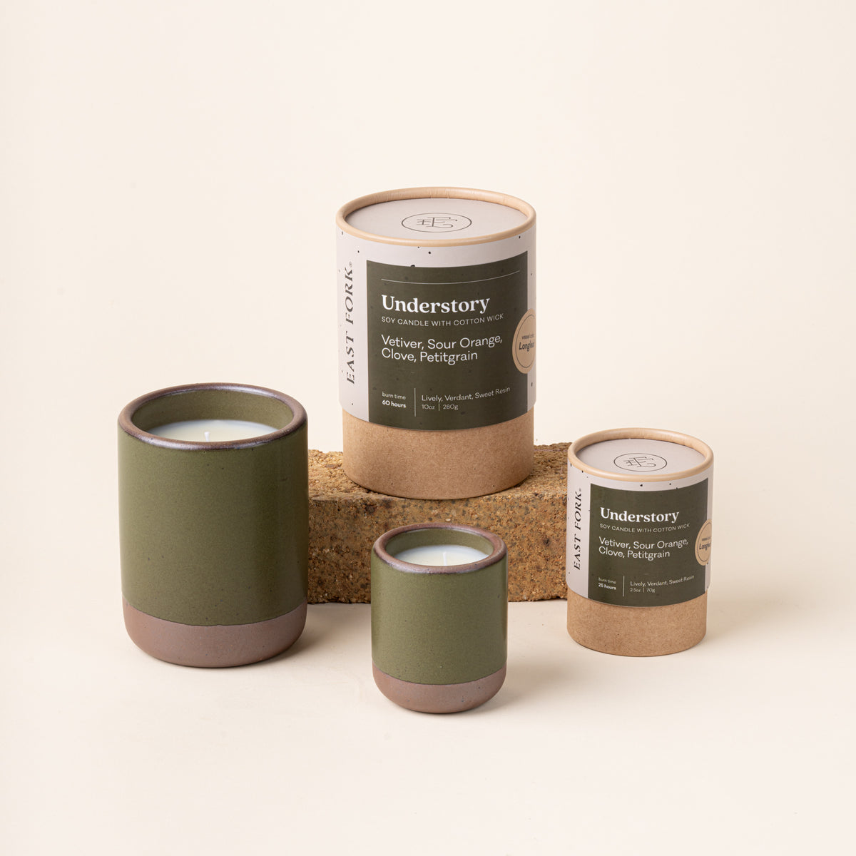 Small and large ceramic vessels in an olive green color with candle inside each with packaging.