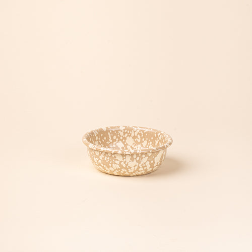 A small enamel bowl in neutral tan color with off-white splatter pattern.