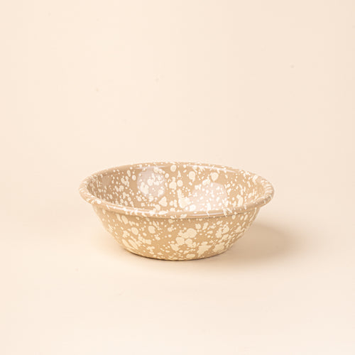 A large enamel bowl in neutral tan color with off-white splatter pattern.