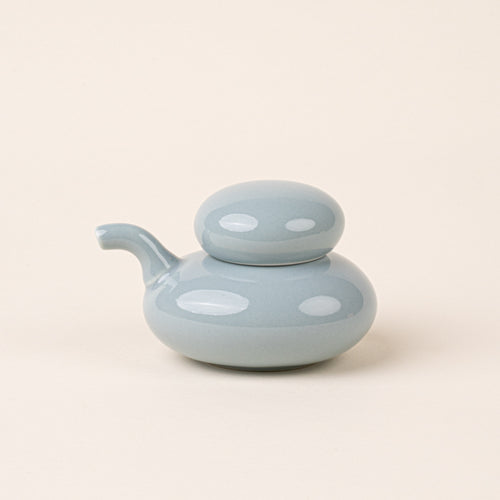 A pale blue glazed ceramic soy sauce pot with a low, rounded body, short pouring spout, and domed lid.