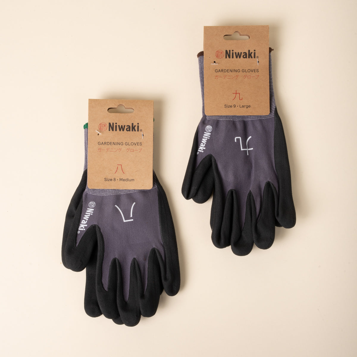 Two pairs of Niwaki gardening gloves in packaging, gray and black with green trim, labeled medium and large.