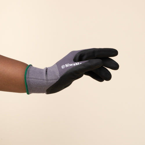 A hand wears a gray and black gardening glove with green trim.