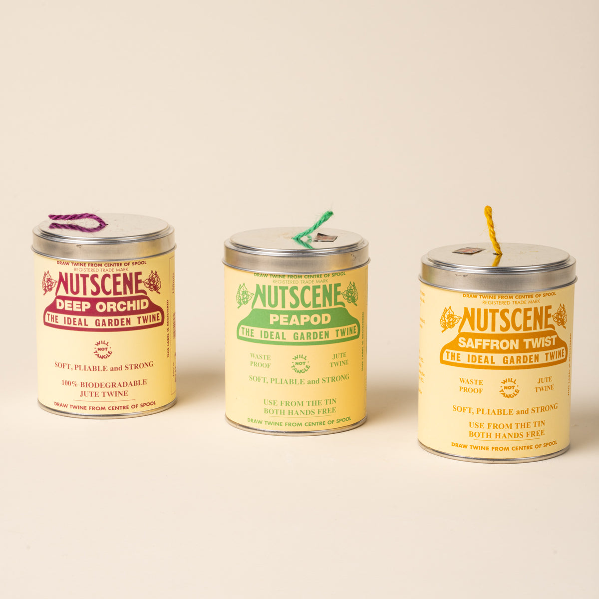 Three tins of Nutscene garden twine in different colors, labeled Deep Orchid, Peapod, and Saffron Twist.