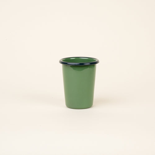 A short green enamel tumbler with a dark rim, set against a soft beige background.