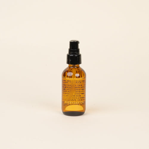 Amber glass bottle with black cap and label that reads 'Warm Feelings Everyday Oil' on a beige background.