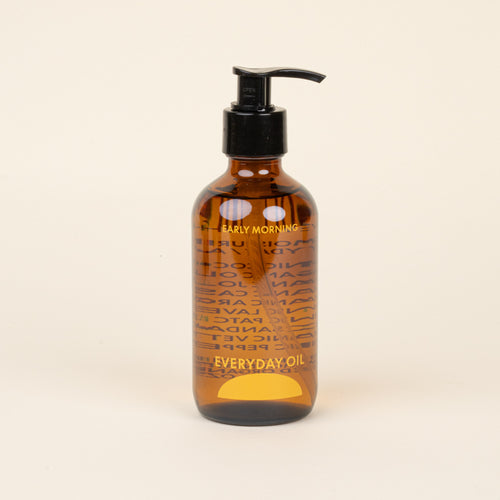 Brown bottle with pump labeled 'Early Morning Everyday Oil' on a beige background