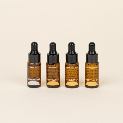 Four bottles of Everyday Oil on a beige background
