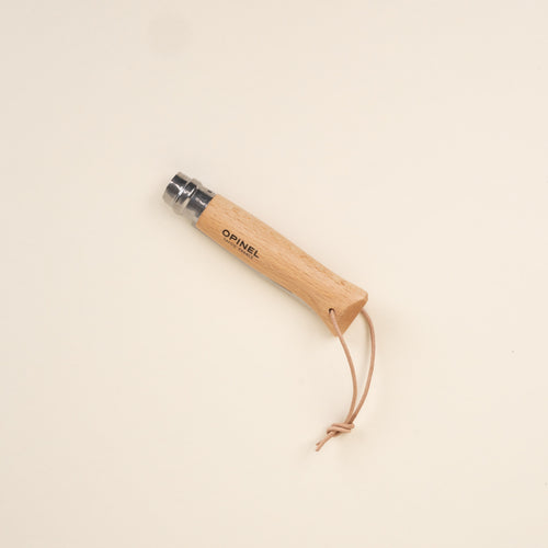 Closed wood-handled folding knife with stainless steel blade and leather lanyard.