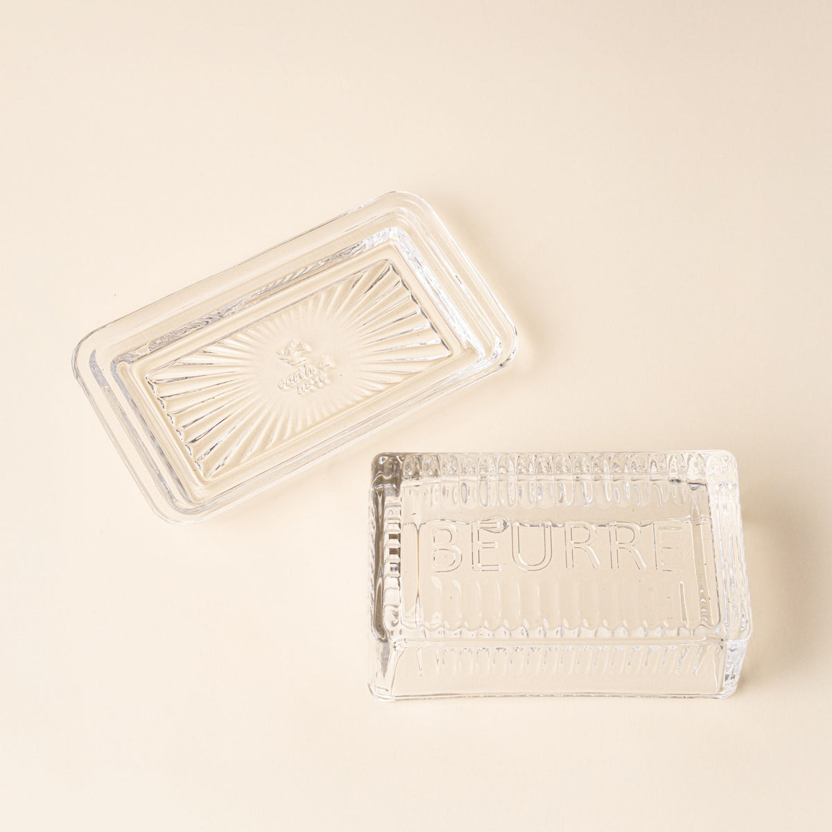 Clear glass butter dish with lid and base on a light background