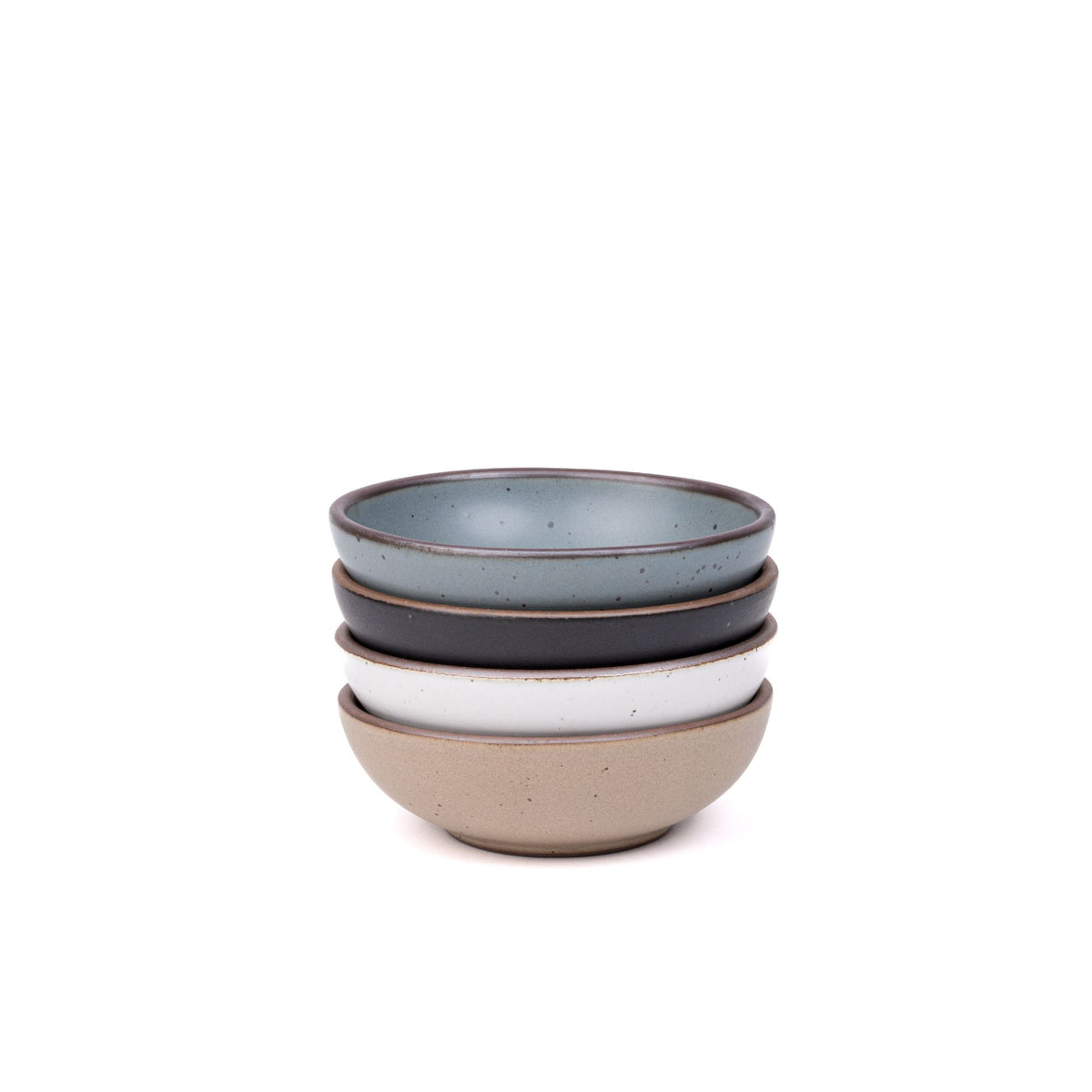 A stack of 4 small shallow ceramic bowls in a blue-grey, graphite black, cool white, and warm pale brown colors featuring iron speckles and an unglazed rim