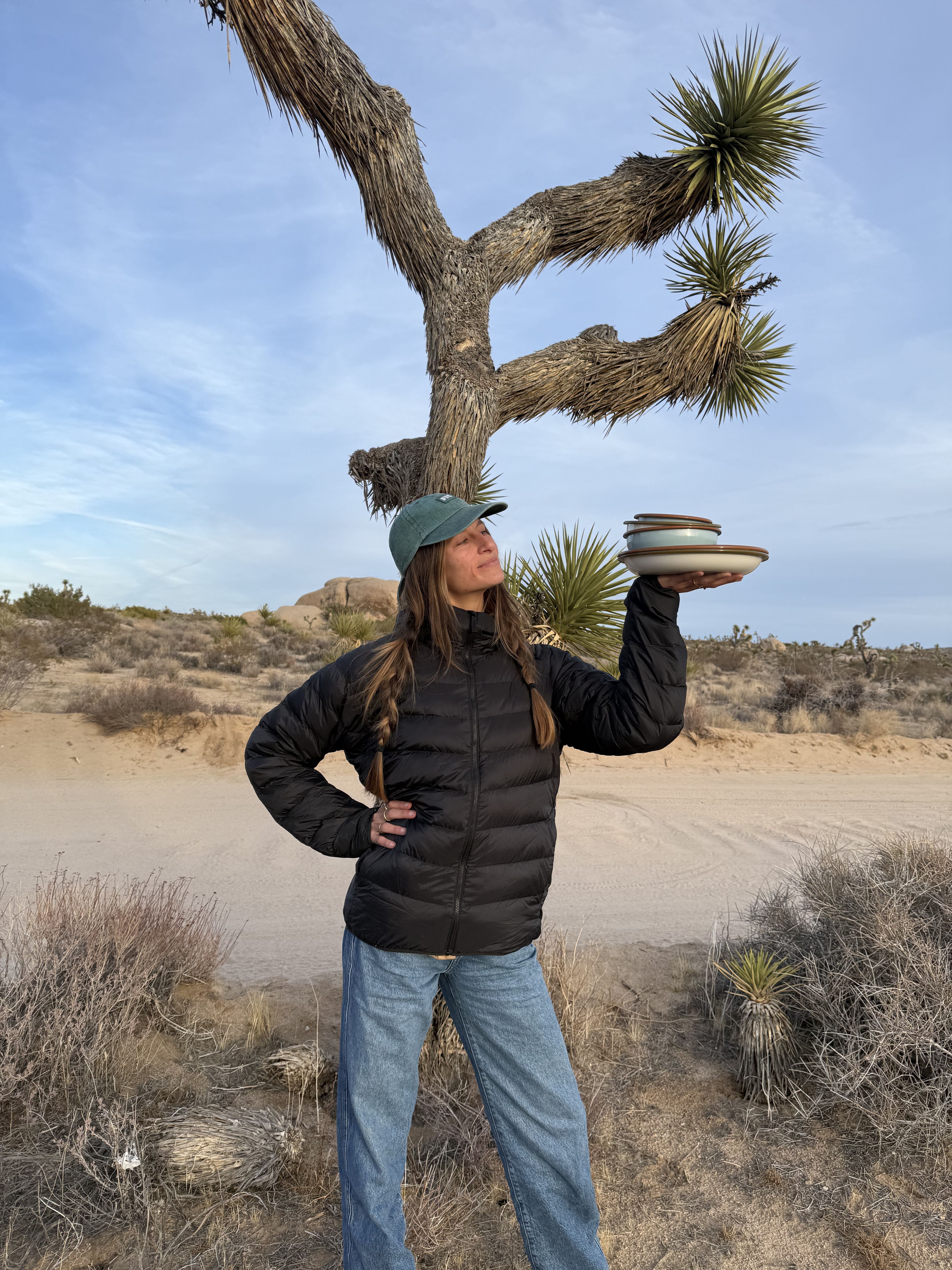 Women holds East Fork enamelware in front of a Joshua Tree