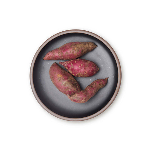 Sweet potatoes on a dinner sized ceramic plate in a graphite black color featuring iron speckles and an unglazed rim.