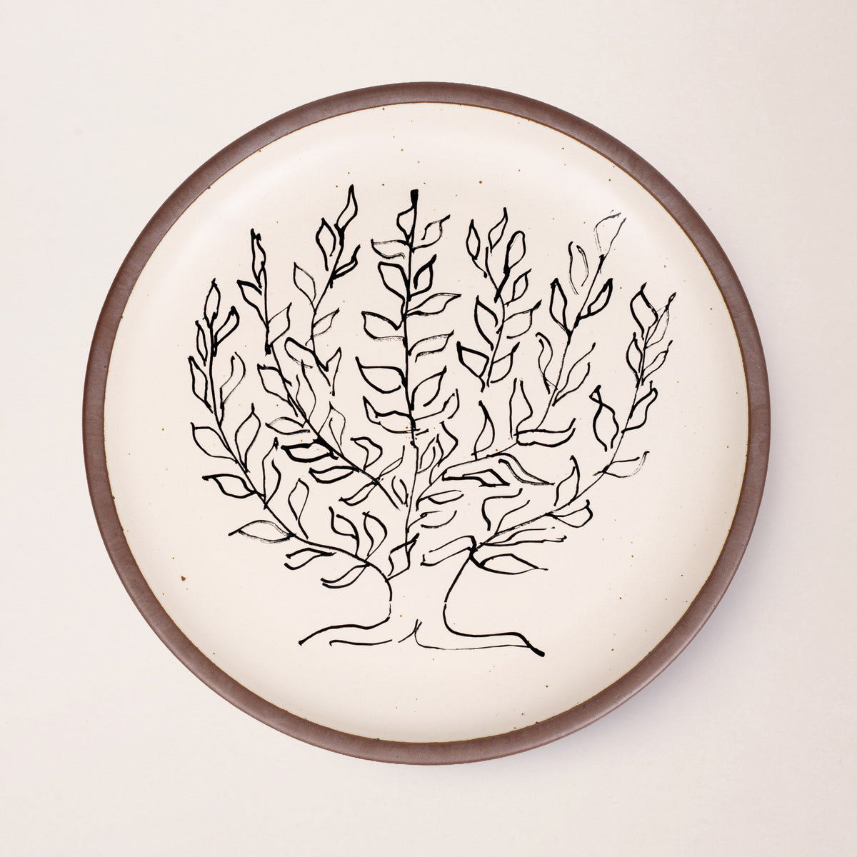 A large serving platter in a warm off-white color with unglazed rim with a black decal of the artwork, Le Platane, from Henri Matisse.