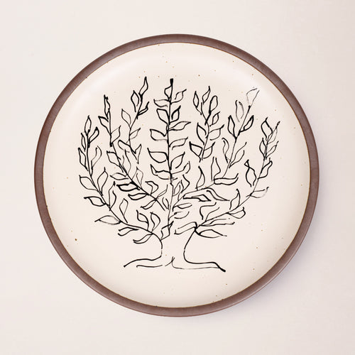 A large serving platter in a warm off-white color with unglazed rim with a black decal of the artwork, Le Platane, from Henri Matisse.