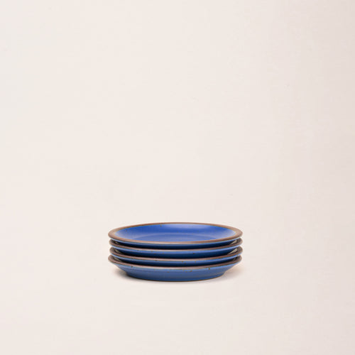 4 dessert sized ceramic plates in a cobalt blue color featuring iron speckles and an unglazed rim.