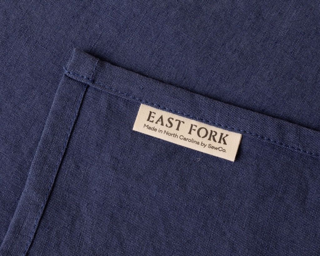 A close up of the corner of a linen napkin with a tag that reads