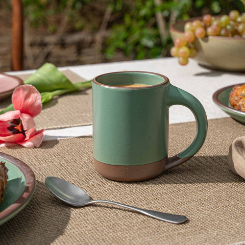Ceramic mug with straight sides and handle, made from iron-rich speckled stoneware with a raw rim in a viridian green glaze with a matte finish.
