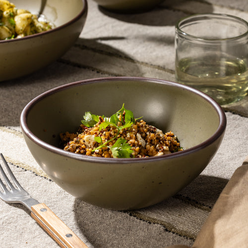 Olive-toned stoneware soup bowl with a grain salad, shown alongside coordinating tableware.