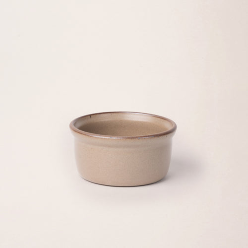 Medium ceramic ramekin in a warm pale brown color with an unglazed rim