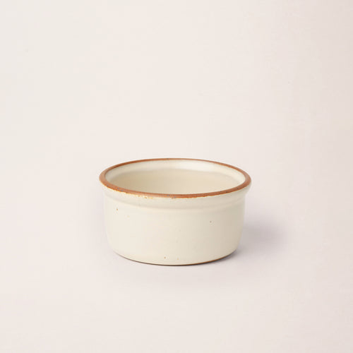 Medium ceramic ramekin in a warm off-white color with an unglazed rim
