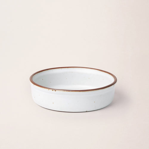 Wide shallow ceramic ramekin in a cool white color with an unglazed rim