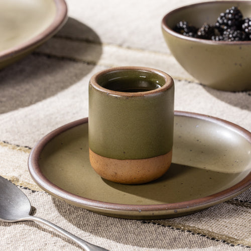 Olive-toned stoneware tumbler cup on a matching small plate