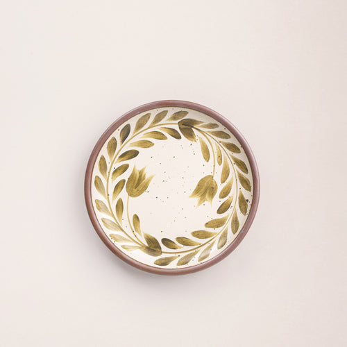 Side round ceramic plate with a hand-painted olive green leaf wreath and floral design on a cream background with an exposed clay rim.