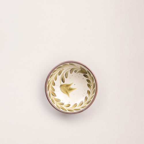 Overhead view of a Small ceramic shallow bowl with a hand-painted olive green leaf border on a cream interior and speckled cream exterior with an exposed clay rim.