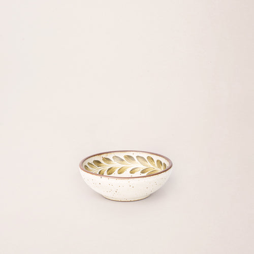 Small ceramic shallow bowl with a hand-painted olive green leaf border on a cream interior and speckled cream exterior with an exposed clay rim.