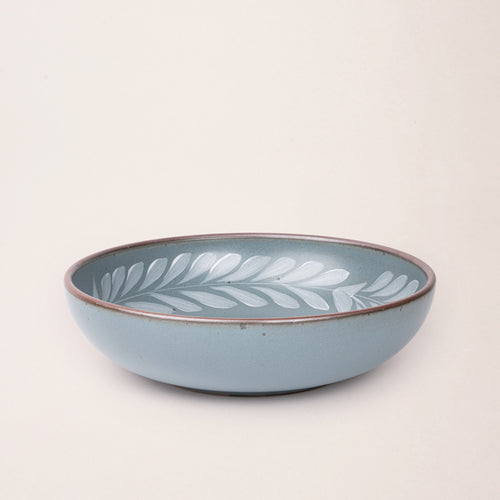 Large ceramic shallow bowl with a hand-painted white leaf border on a blue-grey interior and exterior with an exposed clay rim.