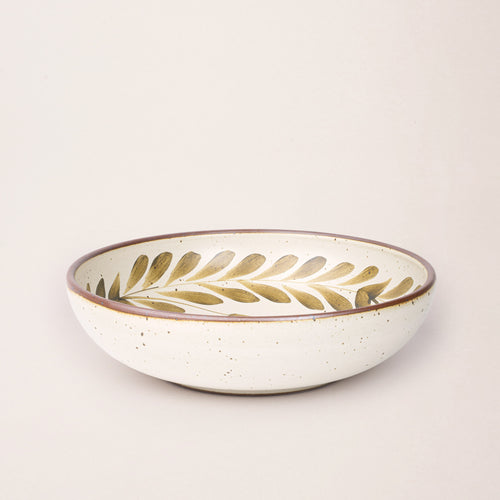 Large ceramic shallow bowl with a hand-painted olive green leaf border on a cream interior and exterior with an exposed clay rim.