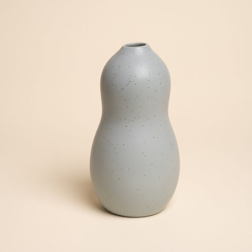 Large blue-grey ceramic vase with a curvy shape and subtle speckles, set against a soft beige background.