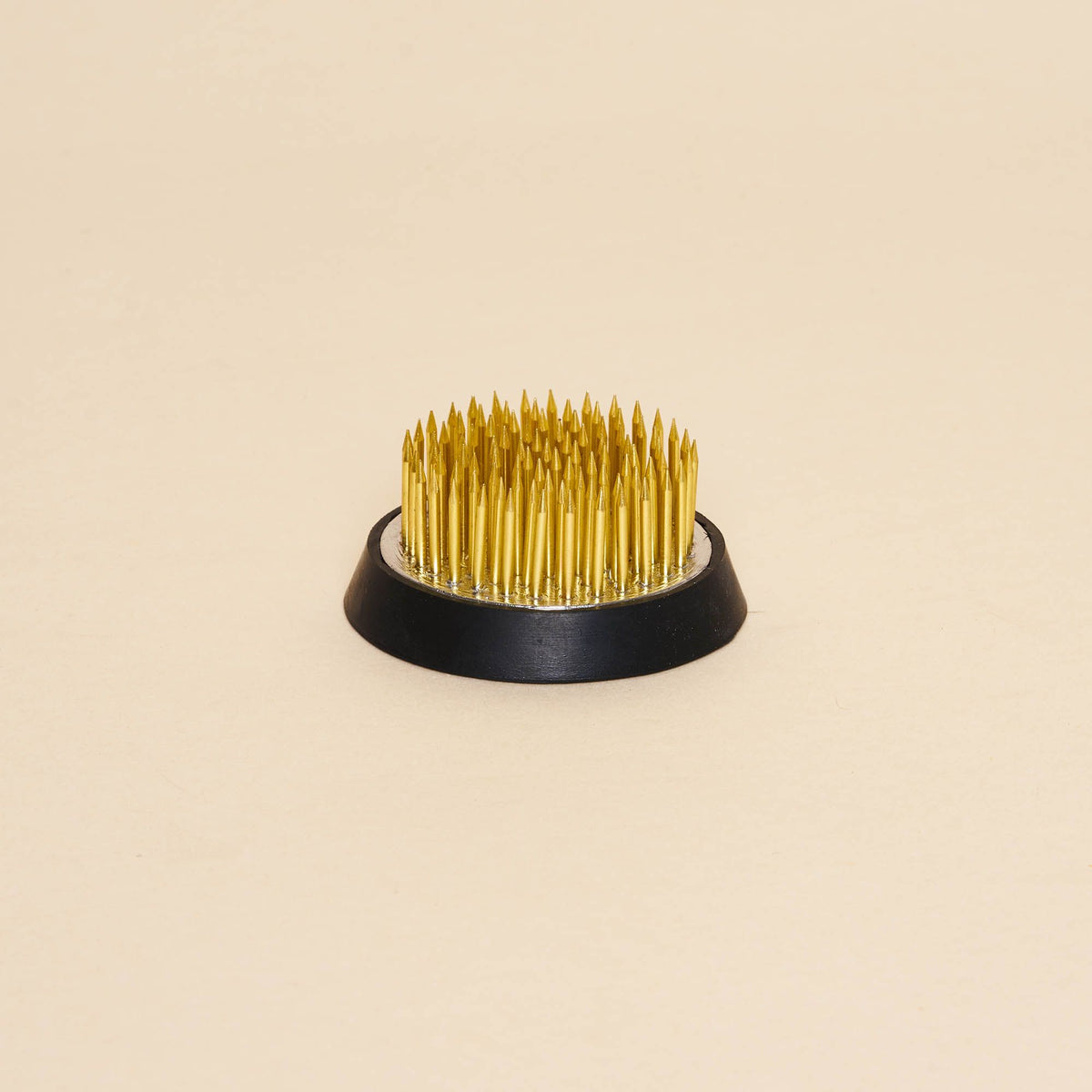 A small "kenzan" – a pin frog made of brass spikes on a flat circular base to assist in flower arrangements.