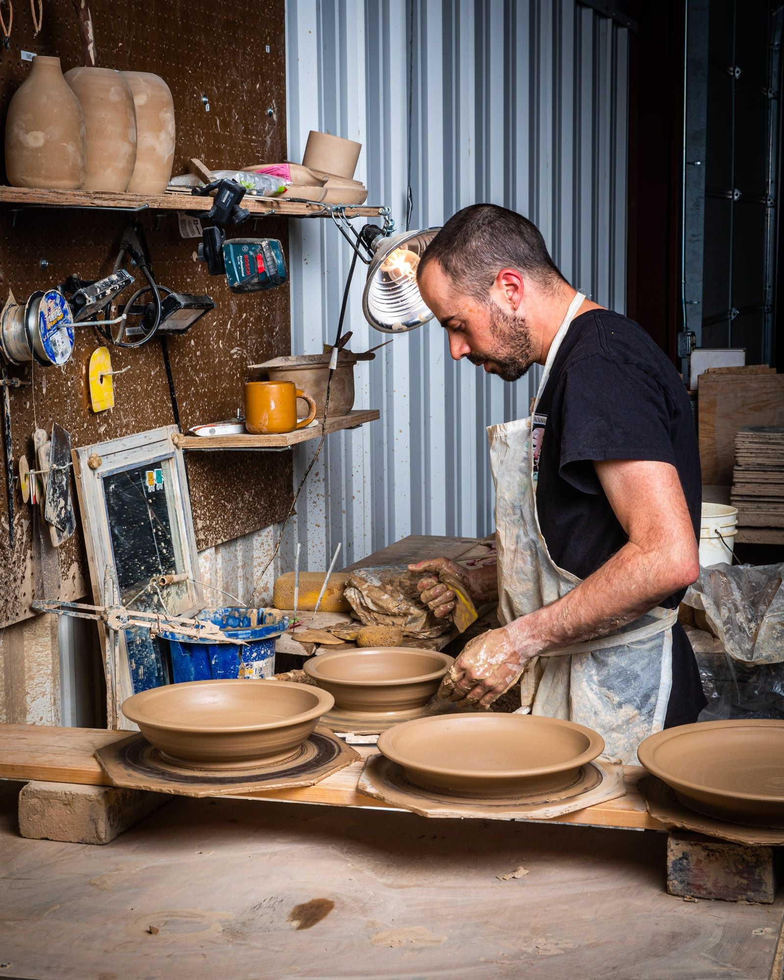 Alex in the new workshop space, at the pottery wheel creating large shallow bowls.