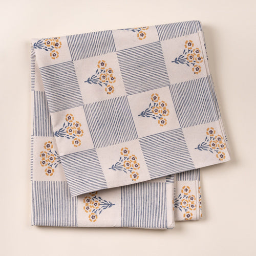 Folded blue-and-white checkered cloth tablecloth printed with small yellow flower bouquets on a light background.