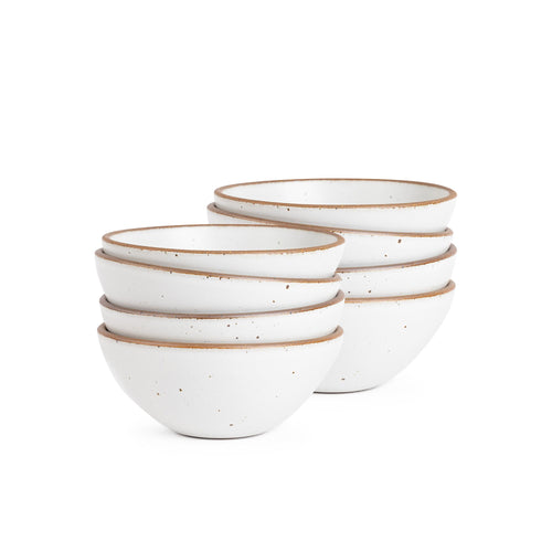 A stack of 8 medium rounded ceramic bowls in a cool white color featuring iron speckles and an unglazed rim