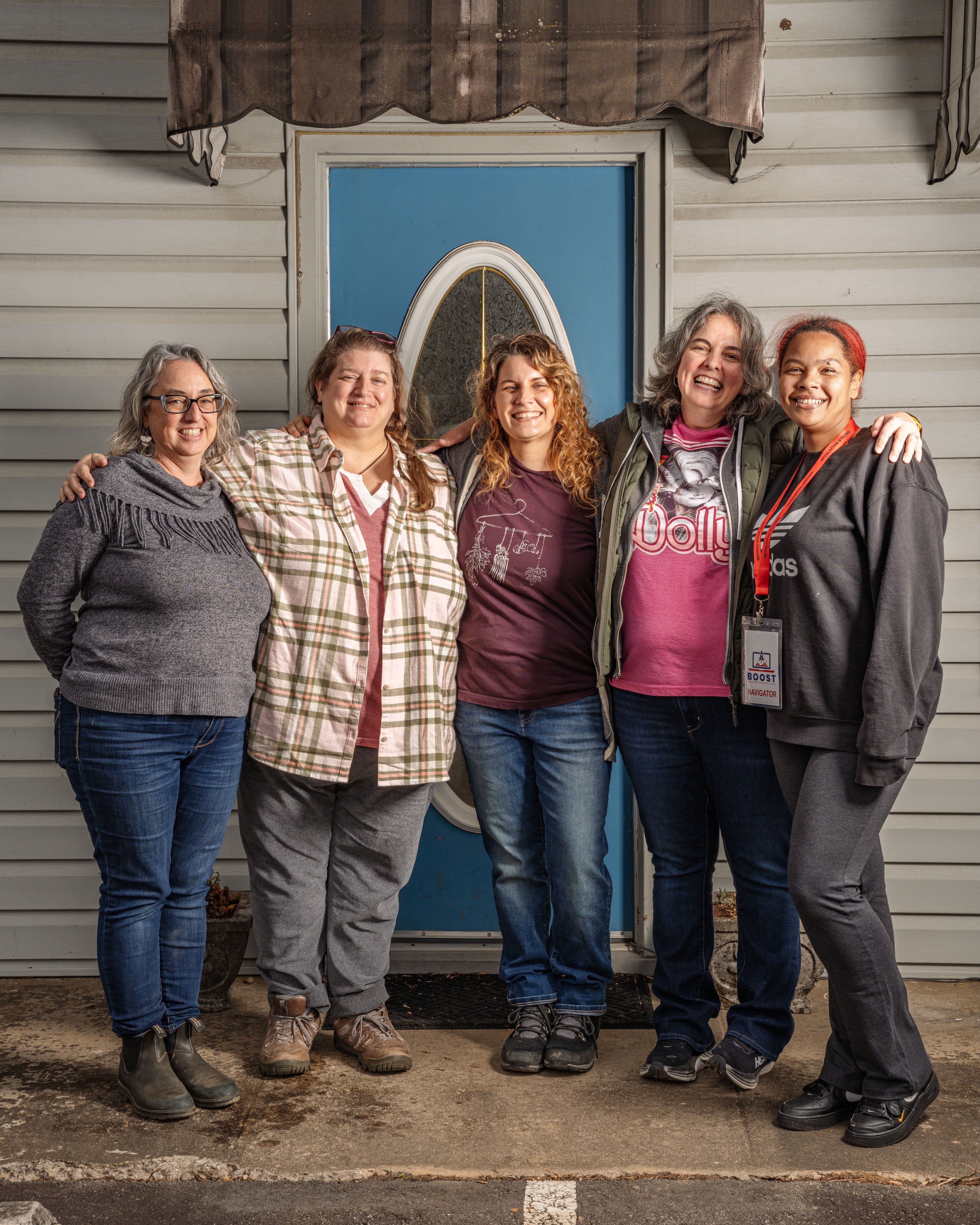 Five members of Swannanoa Communities Together standing in a line together smiling in front of their office space.