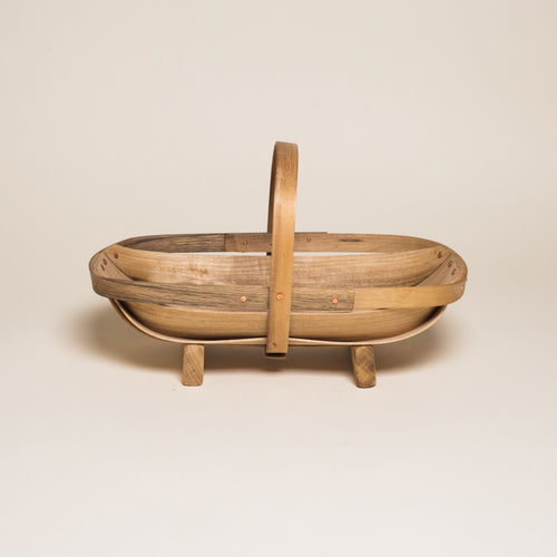 A hand reaches for a large myrtlewood trug for harvesting