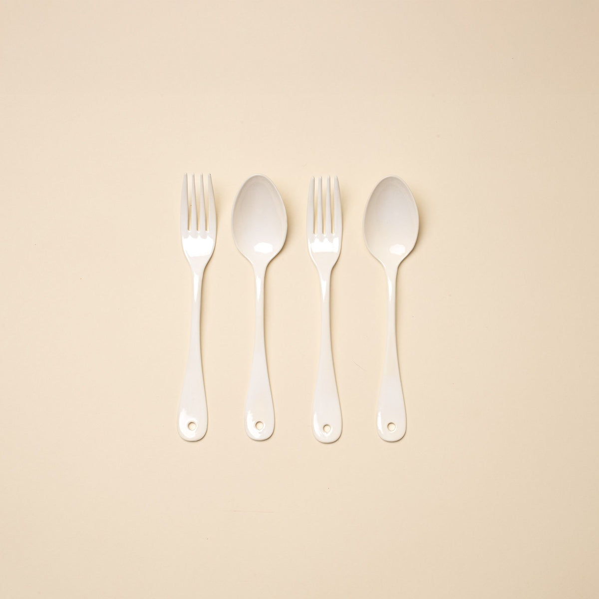 2 dinner forks and 2 dinner spoons made of white enamel lined in a row.
