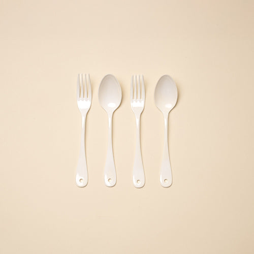 2 dinner forks and 2 dinner spoons made of white enamel lined in a row.