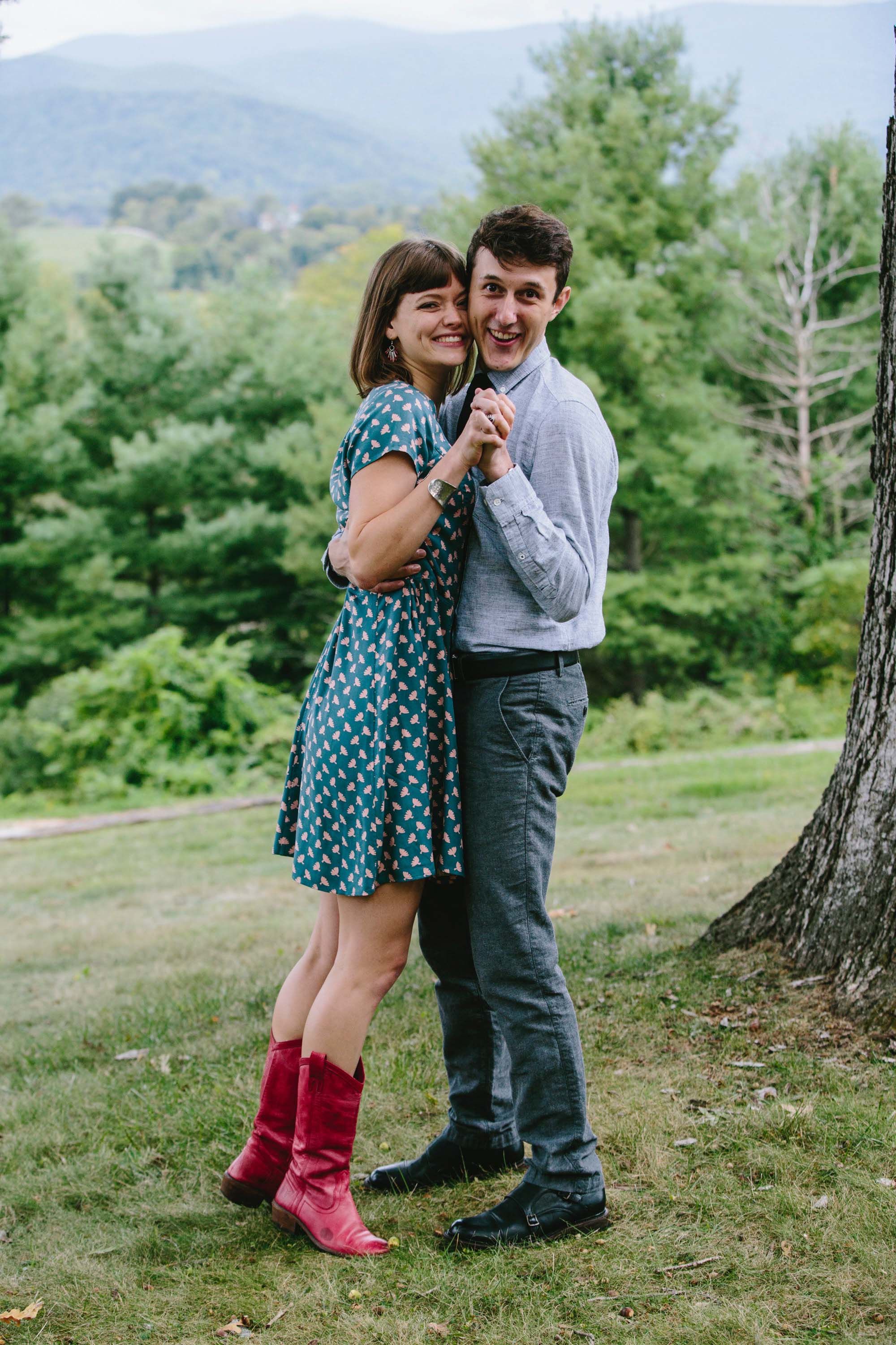 A photo of Eva and James close together and holding hands against a beautiful outside landscape