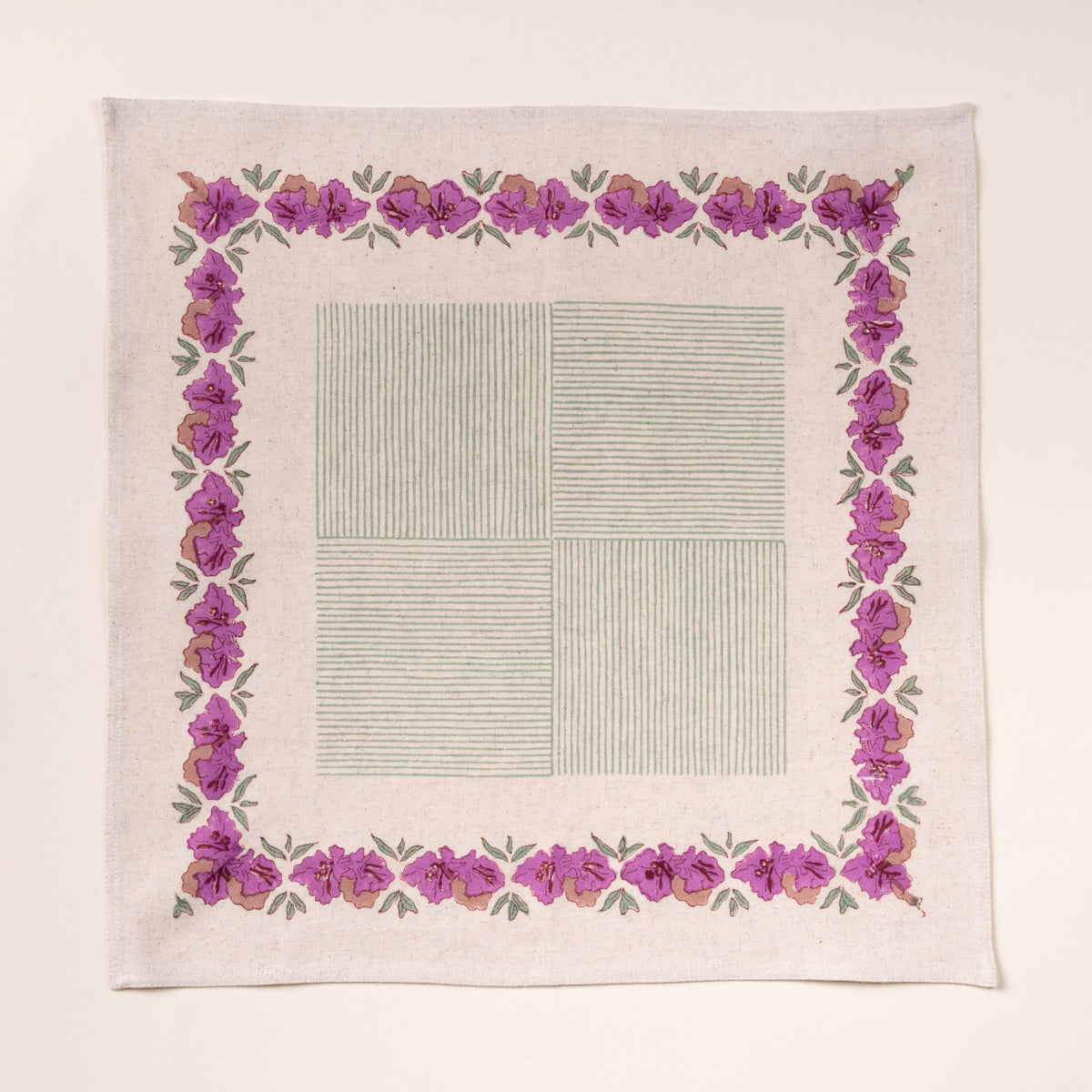 Square cotton napkin with a purple floral border and a pale green striped center design, laid flat on a cream background.