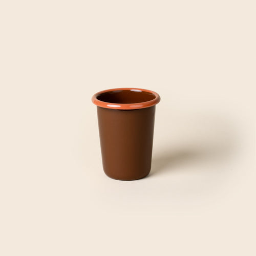 A short red-brown enamel tumbler with an orange rim, set against a soft beige background.