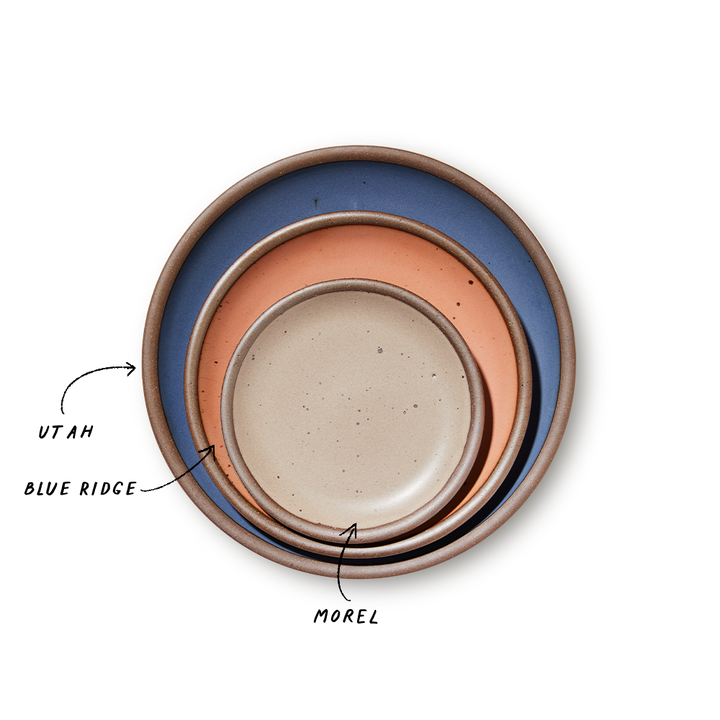A stack of 3 plates in Dinner, Side, and Cake sizes in a navy, peach, and pale warm brown colors.