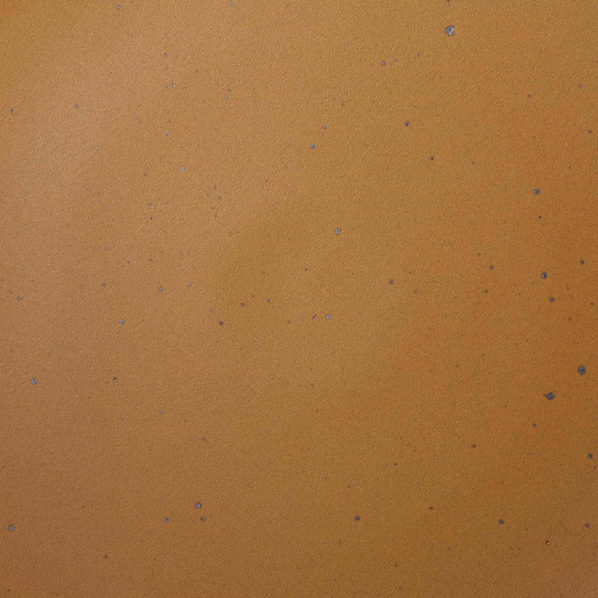 A closeup of a ceramic plate in a dark gold color with iron speckles throughout