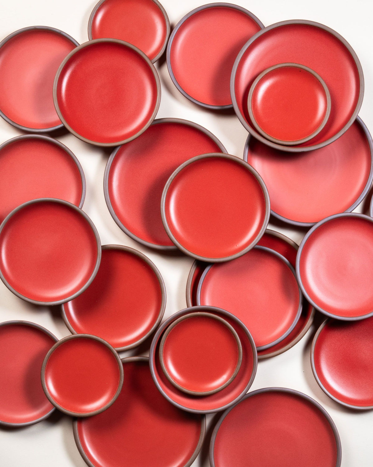 An overhead view of ceramic plates in subtle various shades of a bold red.
