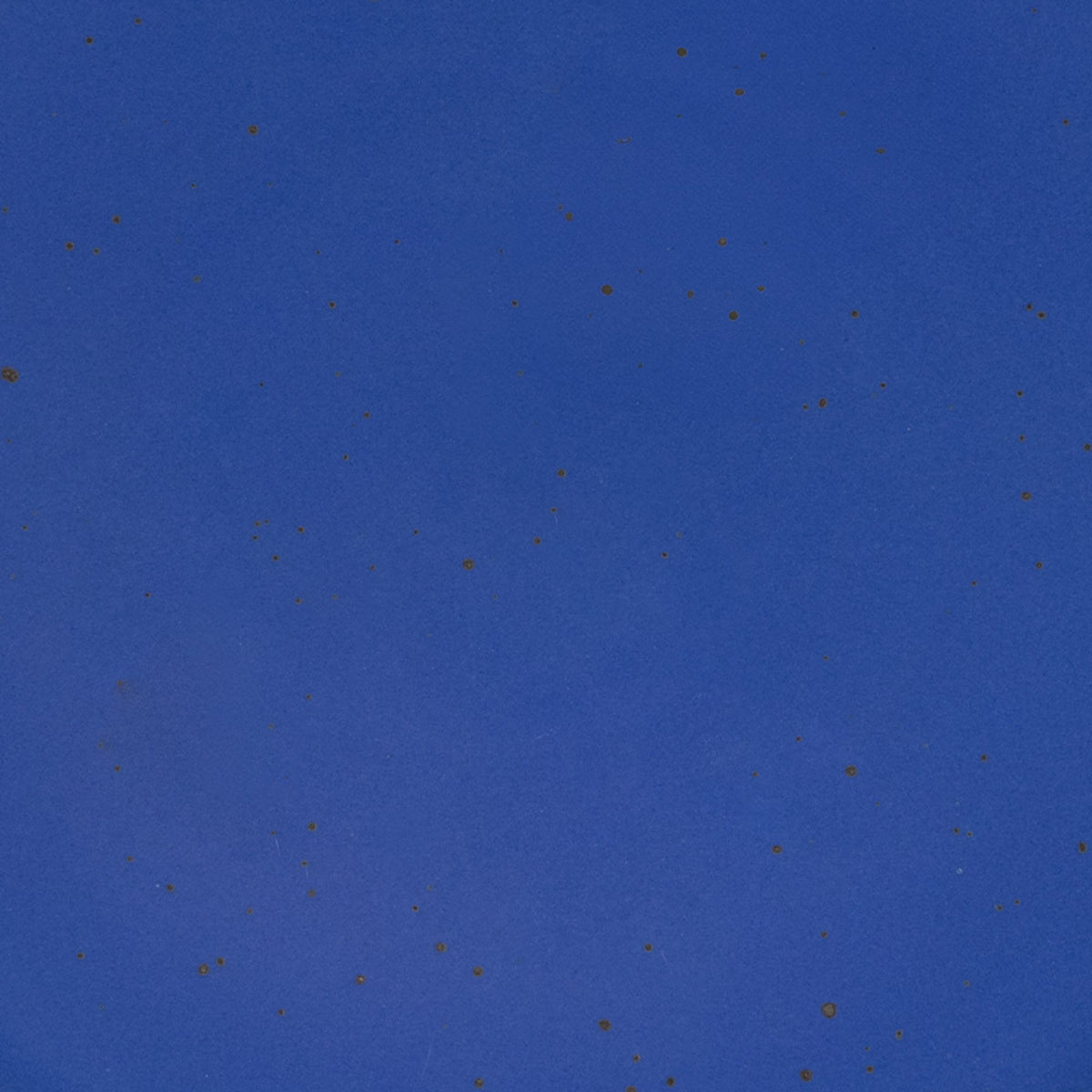 A closeup of a ceramic plate in a cobalt blue color with iron speckles throughout