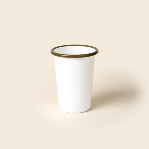 A tall white enamel tumbler with an olive green rim, set against a soft beige background.