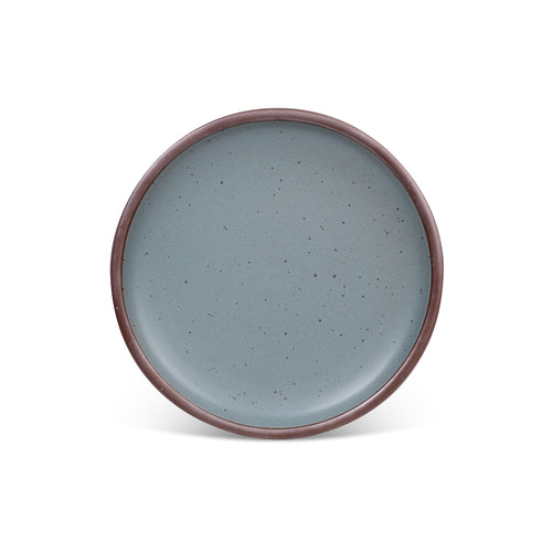A dinner sized ceramic plate in a blue-grey color featuring iron speckles and an unglazed rim