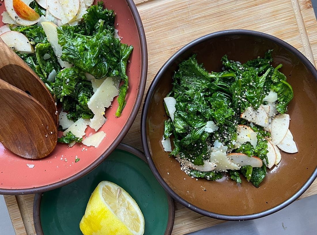 An overhead shot of salad in brown and green bowls and a half a lemon on a green plate.